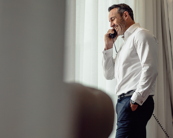 Mann steht am Fenster und telefoniert