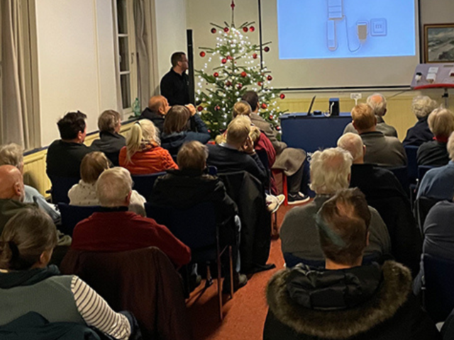 Saal mit mehreren Personen die sitzen und eine Präsentation anschauen