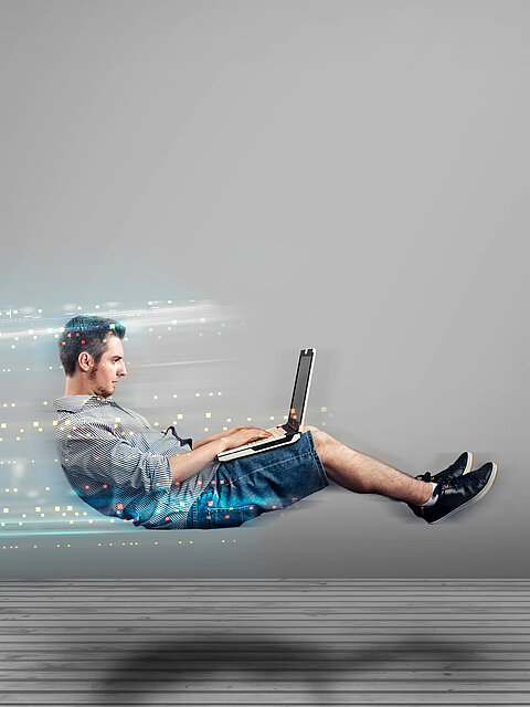 Ein Mann arbeitet mit einem Laptop, während leuchtende digitale Datenspuren Geschwindigkeit und eine schnelle Internetverbindung symbolisieren.
