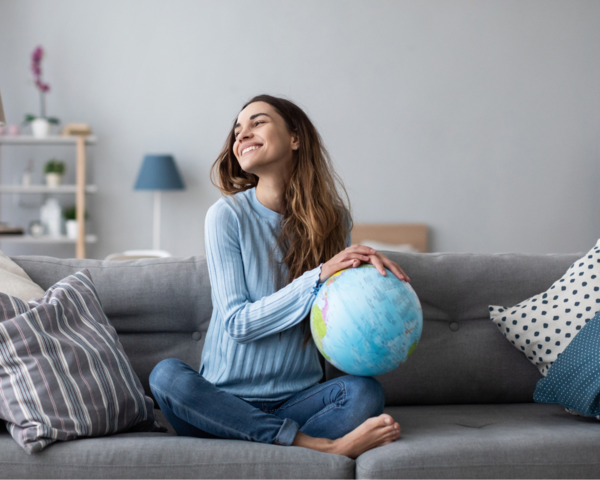 Frau sitzt auf dem Sofa mit einem Globus in der Hand