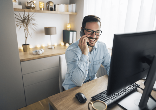 Mann sitzt am PC und telefoniert dabei